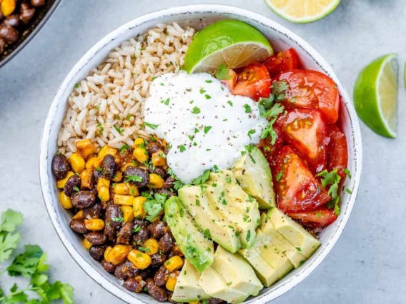 Vegetarian burrito bowl with rice, beans, corn, avocado, and tomato. 