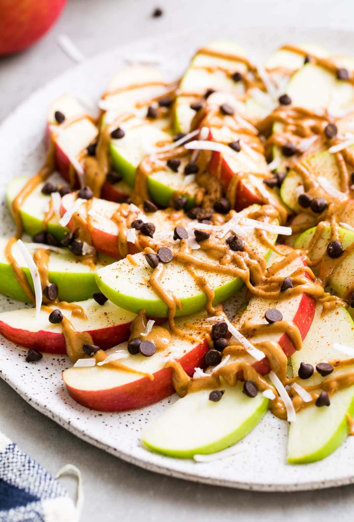 Sliced apples with peanut butter drizzle, chocoloate chips, and nuts