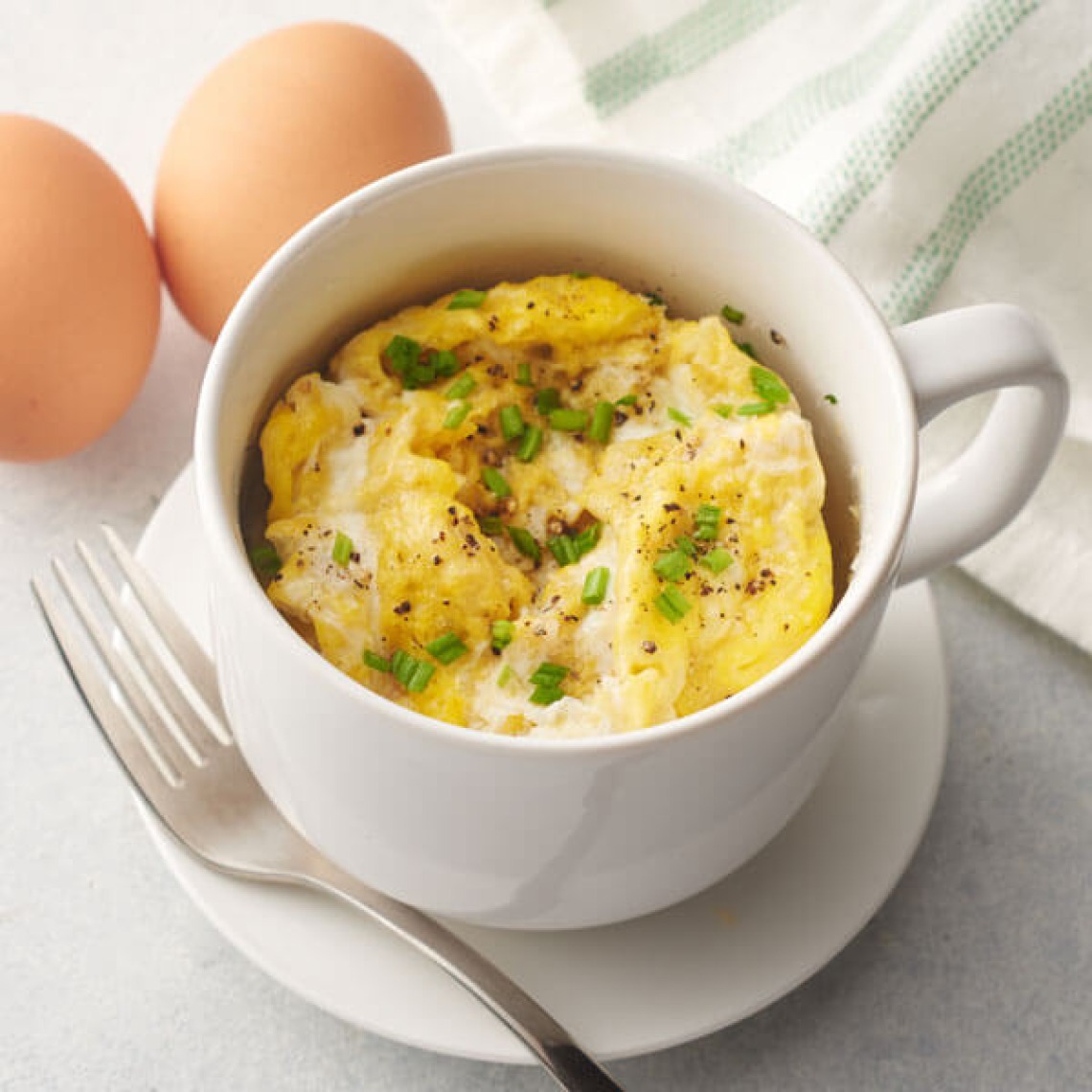 Eggs in an Omlette inside of a mug with green onion topping